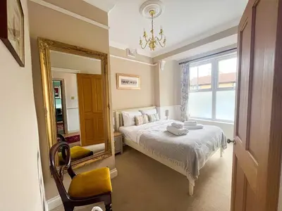a bedroom with a bed and a mirror and a chair at Luxury 1 Bedroom Apartment in Southend w Parking in Southend-on-Sea