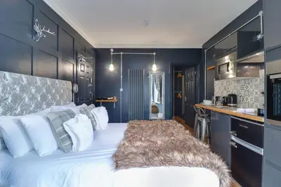 a bedroom with a large white bed and a kitchen at Studio Apartments in Southend in Southend-on-Sea