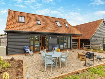 a house with a patio with a table and chairs at Gladwyns Farm Lodge in Thaxted
