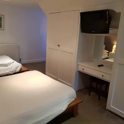 a bedroom with a bed and a dresser with a television at Heritage Grange at Thurston, Hotel in Bury Saint Edmunds