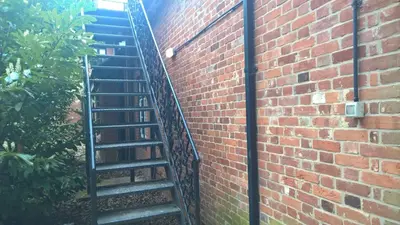 a spiral staircase next to a brick wall at Heritage Grange at Thurston, Hotel in Bury Saint Edmunds