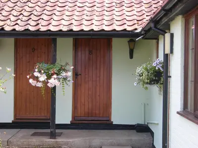 a house with two wooden doors and flowers on it at Six Bells Inn in Bardwell