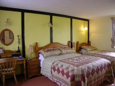 a bedroom with two beds and a desk with a mirror at Six Bells Inn in Bardwell