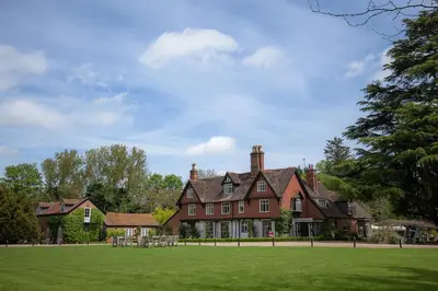a large red brick house with a grass field at Ravenwood Hall Hotel in Bury Saint Edmunds