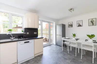 a kitchen with white cabinets and a table with chairs at Entire House - Contractor's, Families & More in Little Wymondley