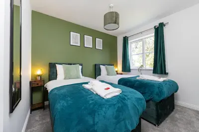 two beds in a room with green walls at Entire House - Contractor's, Families & More in Little Wymondley