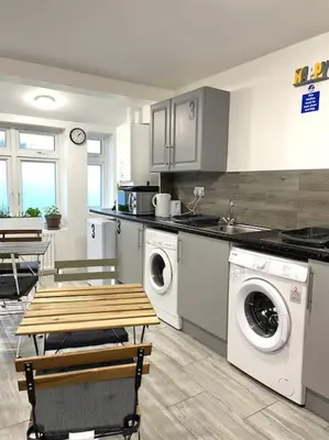 a kitchen with a washer and dryer and a table at 12 Penn Gardens Standard Room- 4 in Friern Barnet