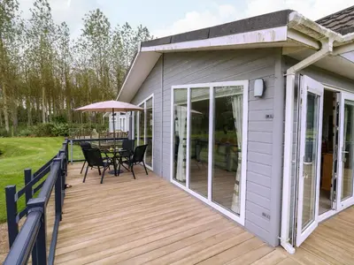 a large deck with a table and chairs on it at Owls Retreat, Lodge 11 in Aldeburgh