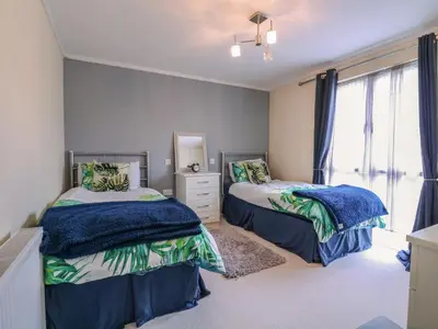 a bedroom with two beds and a mirror at Owls Retreat, Lodge 11 in Aldeburgh