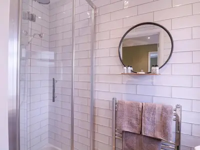 a bathroom with a shower and a mirror at The Farmhouse in Clacton-on-Sea