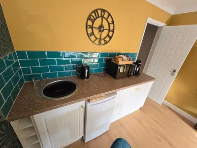 a kitchen counter with a sink and a clock on the wall at Munnings Lodge Apartment in Mendham