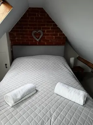 a bedroom with a bed with two pillows on it at Cosy 2 bed cottage in beautiful Orford in Orford