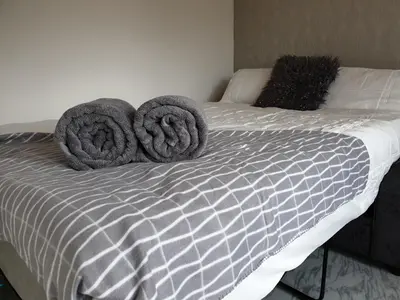 a bed with gray towels on top of it at Room Stay - Marks tey, Colchester, United Kingdom in Marks Tey