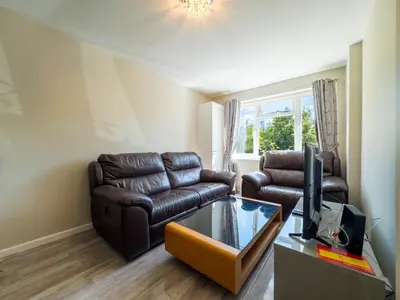 a living room with two leather couches and a television at 5 bedroom with Prking in Laindon