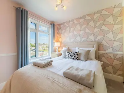 a bedroom with a large bed with a window at 5 bedroom with Prking in Laindon