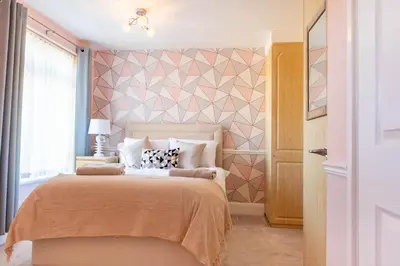 a bedroom with a bed with a geometric accent wall at 5 bedroom with Prking in Laindon