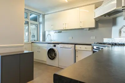 a large kitchen with a washer and dryer in it at 5 bedroom with Prking in Laindon