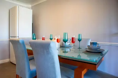 a dining room table with blue chairs and a glass table with glasses at 5 bedroom with Prking in Laindon