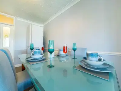 a glass table with plates and wine glasses on it at 5 bedroom with Prking in Laindon