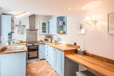 a kitchen with blue cabinets and wooden counter tops at Oriel Cottage, Aldeburgh in Aldeburgh