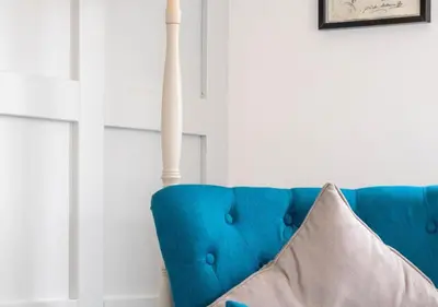 a blue couch in a white room with a pillow at The Keep - Framlingham in Framlingham