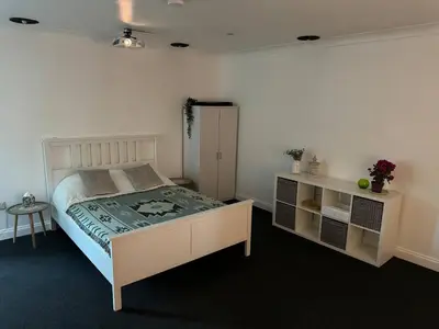 a bedroom with a large bed and a table at Spacious private cinema guest house in Brentwood