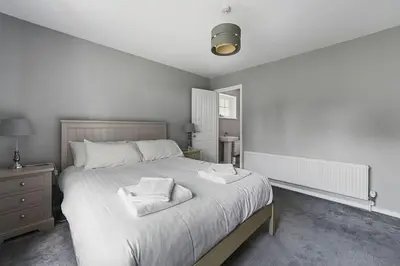 a white bedroom with a large bed with two towels on it at 10 Holly Close in Westley