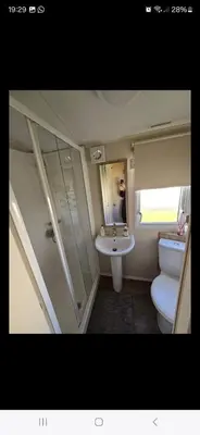 a bathroom with a toilet and a sink and a mirror at 8 berth caravan Martello Beach Clacton in Jaywick Sands