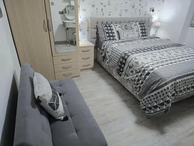 a bedroom with a bed and a couch next to a mirror at Martello Bay Hotel in Clacton-on-Sea
