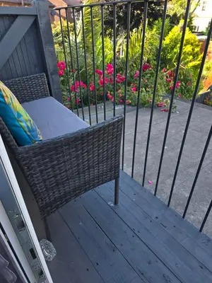 a wicker chair sitting on a deck with pink flowers at Martello Bay Hotel in Clacton-on-Sea