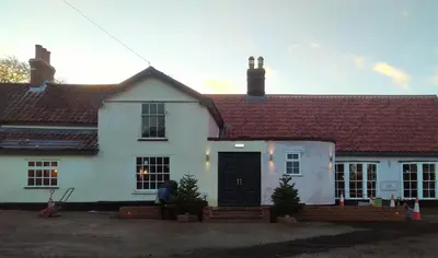 a white house with a black door at Trowel and Hammer Flat 1 in Cotton