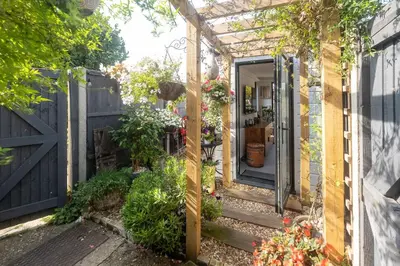 a garden entrance to a house with a pergola at 5 Burrells Cottages in Leiston