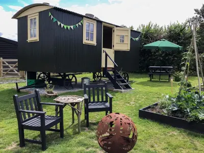 a tiny house with chairs and a table in a yard at Beeches Shepherd Hut in Harleston