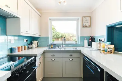 a blue and white kitchen with a sink and a window at Beautiful Aldeburgh Coastal Getaway in Aldeburgh