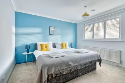 a blue bedroom with a large bed with yellow pillows at Beautiful Aldeburgh Coastal Getaway in Aldeburgh