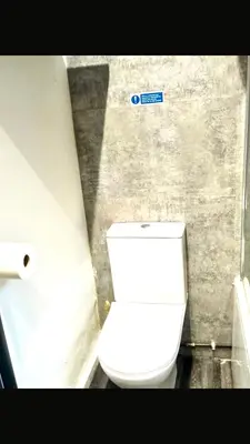 a white toilet in a bathroom with a sign on the wall at Number 14 in Ipswich