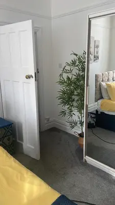 a bedroom with a mirror and a couch and a plant at Right by Leigh Broadway Private Garden large ground fl apt in Southend-on-Sea