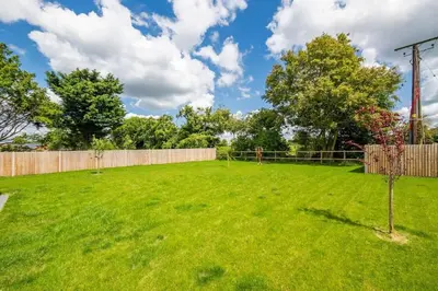 a large yard with a fence and a green lawn at Kestral House in Eye