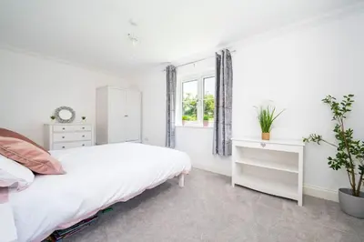 a white bedroom with a bed and a window at Kestral House in Eye