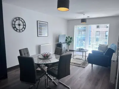 a living room with a table and chairs and a clock at The Sunrise Den-Lovely 2 bedroom apartmentParking in Harlow