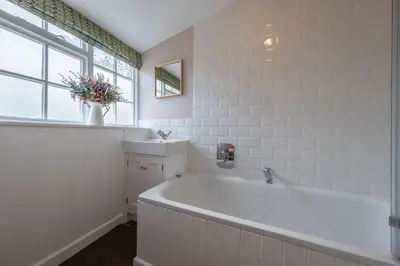 a white bathroom with a tub and a window at Brimming with Medieval charm - Weavers Cottage in Lavenham