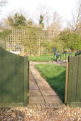a fence with a gate and a bench in a park at The Old Coach House in Bungay