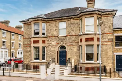 a brick building with a blue door on a street at Tailored Stays - Central Cambridge, Warkworth Lodge in Cambridge