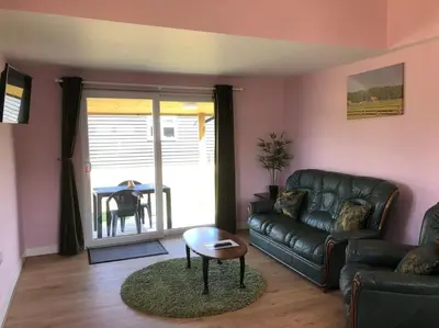 a living room with a leather couch and a table at Wagtail Lodge in Lackford