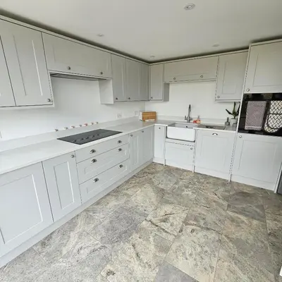 a white kitchen with white cabinets and a tile floor at Field View in Elmswell