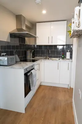 a kitchen with white cabinets and black tiles at The Retreat- amazing scenic views of the Essex countryside! in Salcott