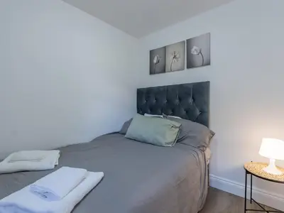 a bedroom with a large bed with two pictures on the wall at Comfortable 2 Bed Apartment Pass the Keys in Basildon
