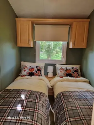 two beds in a small room with a window at The Duck - Free Fishing, pets welcome - static caravan in Clare, Suffolk in Sudbury