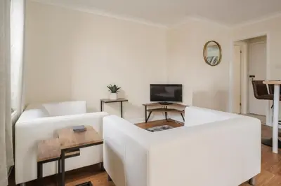 a living room with a white couch and a tv at Ely Stays Flat 1 in Ely