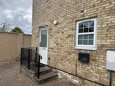 a brick building with a white door and a window at Ely Stays Flat 1 in Ely
